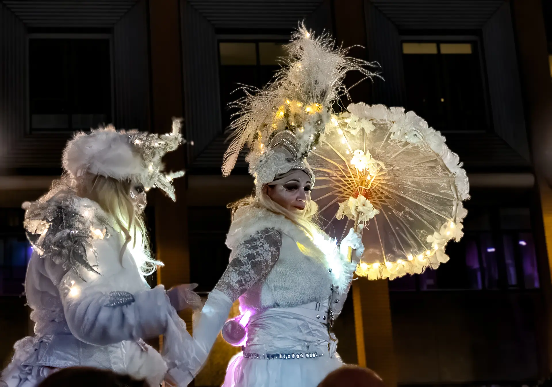 Verlichte artiesten in witte kostuums tijdens de Lichtjesparade